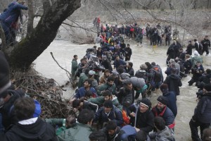 Migrants wade across a river near the Greek-Macedonian border, west of the the village of Idomeni, Greece, March 14, 2016. REUTERS/Stoyan Nenov