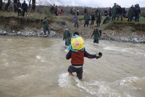 Migrants wade across a river near the Greek-Macedonian border, west of the the village of Idomeni March 14, 2016. REUTERS/Stoyan Nenov