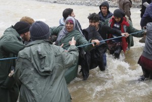 Migrants wade across a river near the Greek-Macedonian border, west of the the village of Idomeni March 14, 2016. REUTERS/Stoyan Nenov