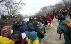 Migrants wade across a river near the Greek-Macedonian border, west of the the village of Idomeni, Greece, March 14, 2016.  REUTERS/Stoyan Nenov