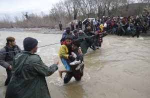 Migrants wade across a river near the Greek-Macedonian border, west of the the village of Idomeni, Greece, March 14, 2016. REUTERS/Stoyan Nenov